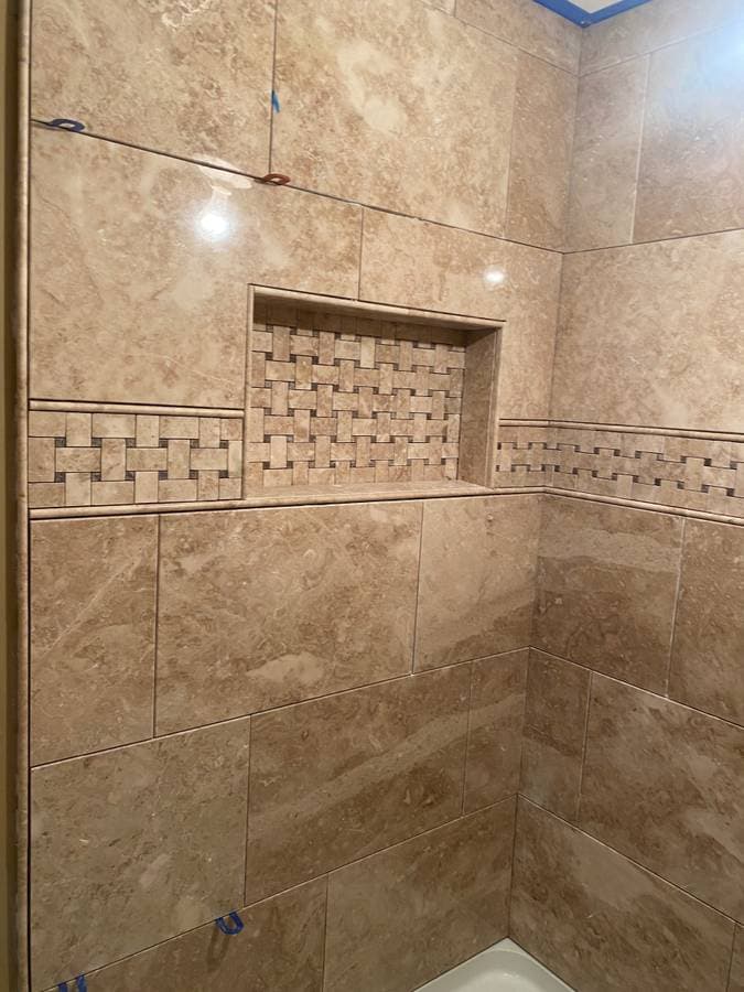 picture of a tile shower with luxury beige tile and tile shelf backsplash